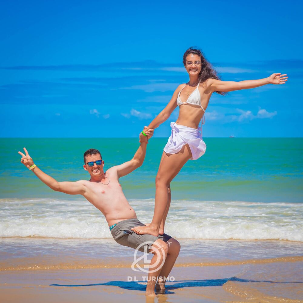 Casal sorrindo em uma pose divertida na praia
