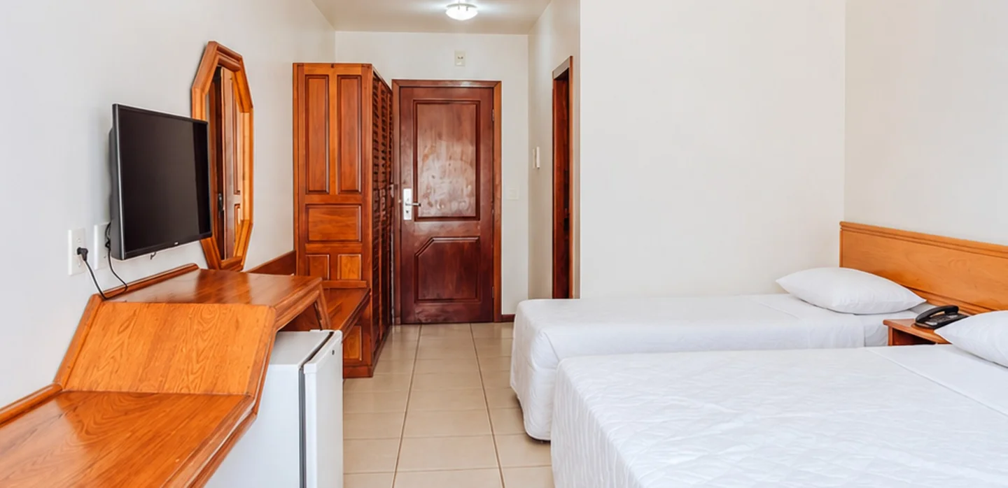 Apartamento com duas camas de solteiro, TV e mesa